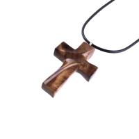 A wooden cross pendant necklace carved in brown wood with black cord. The pendant is intricately detailed and shows the wood grain. This handcrafted necklace is a unique and stylish accessory.