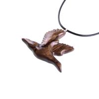 A dark brown wooden duck pendant on a black cord necklace. The bird is carved in flight with its wings spread out.