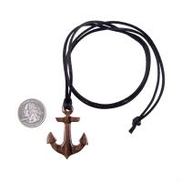 A wooden anchor pendant necklace with black satin cord ending with a knot next to a US quarter for scale.