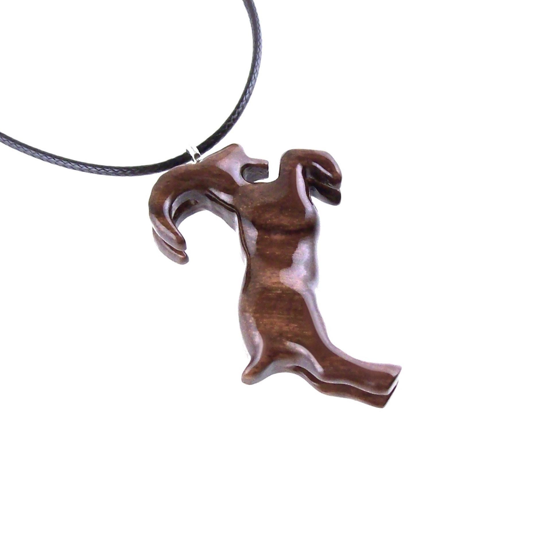A wooden pendant shaped like a goat standing on its hind legs. The pendant is brown and has a natural wood grain pattern. The pendant is hanging from a black cord.