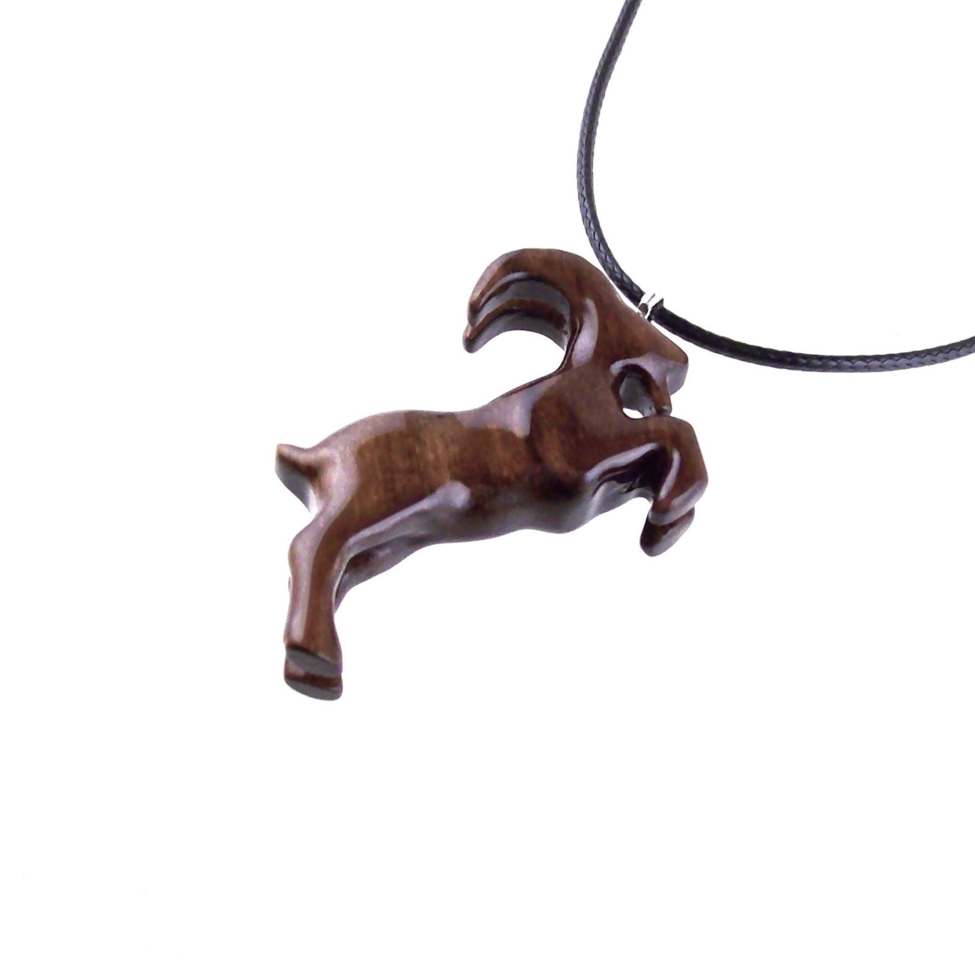 A wooden pendant shaped like a goat standing on its hind legs. The pendant is brown and has a natural wood grain pattern. The pendant is hanging from a black cord.