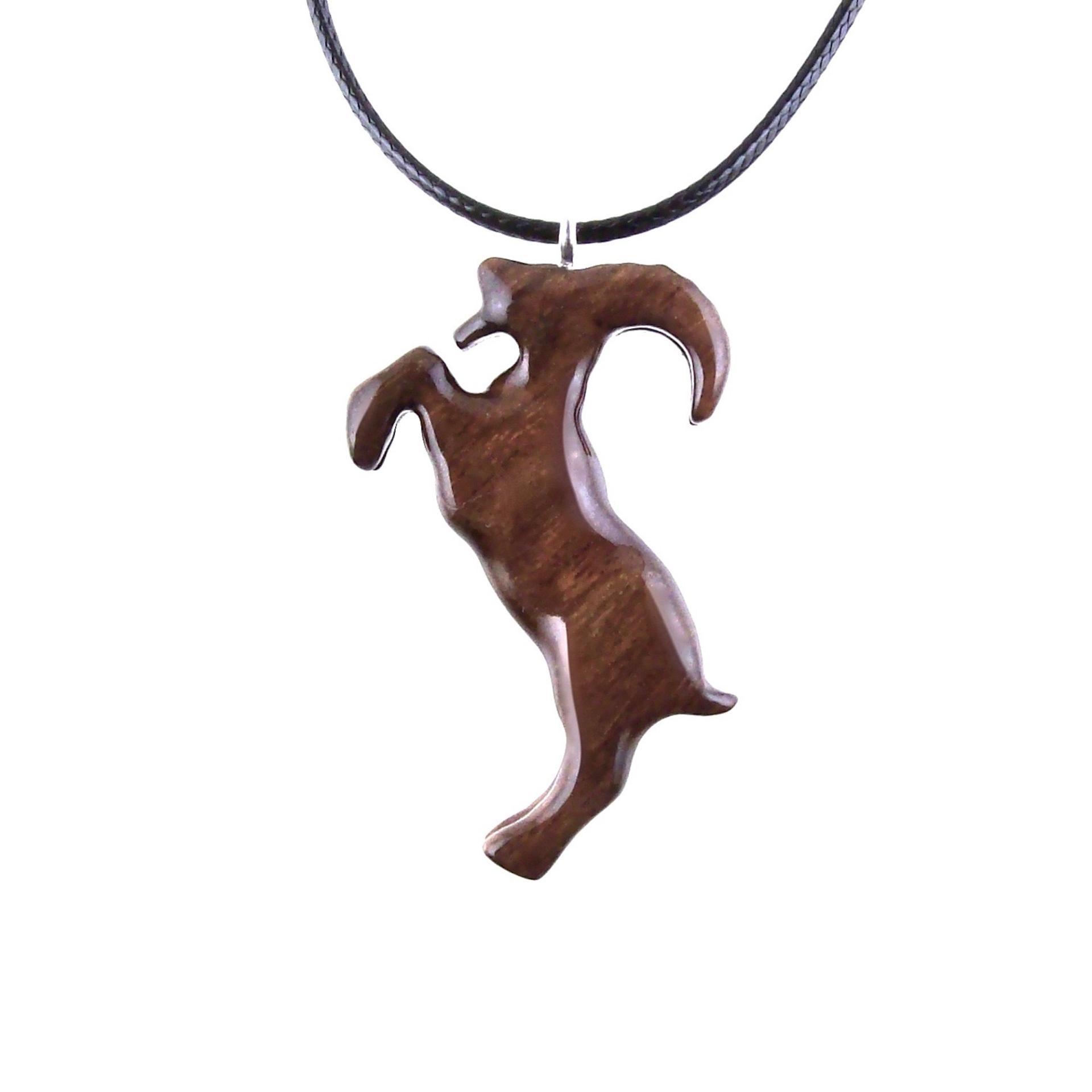 A wooden pendant shaped like a goat standing on its hind legs. The pendant is brown and has a natural wood grain pattern. The pendant is hanging from a black cord.