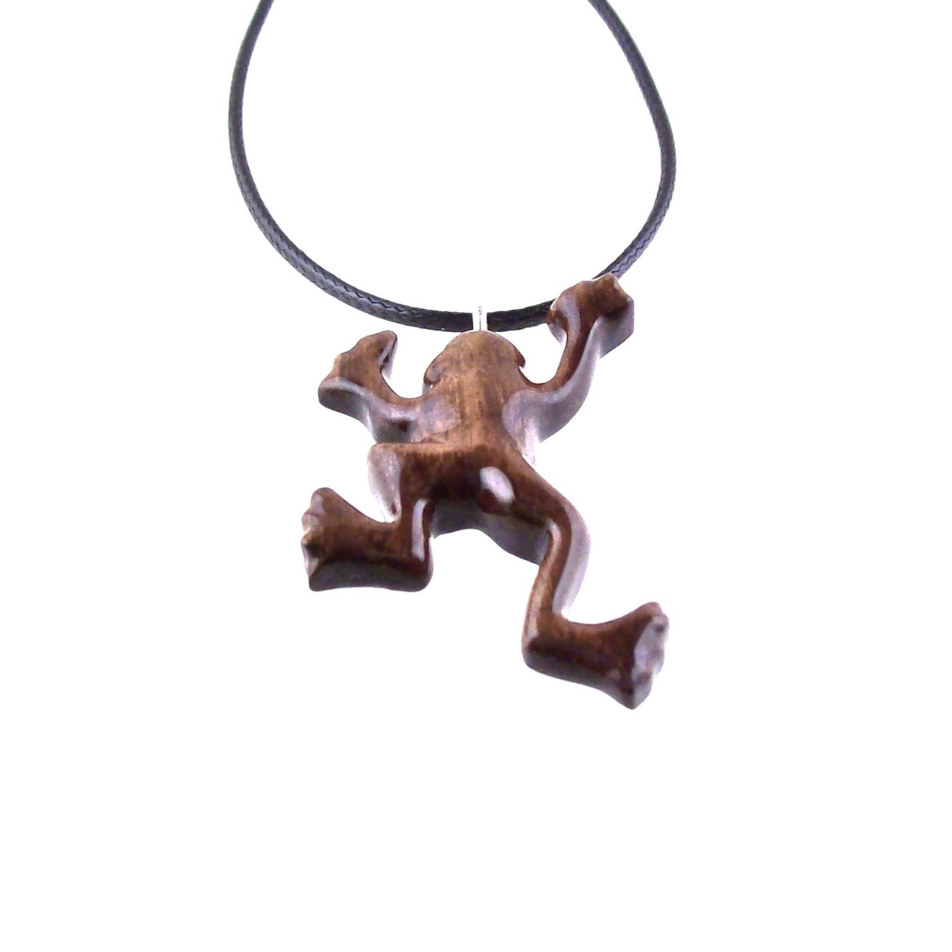 A brown frog pendant on a black cord necklace. The frog is in a jumping pose with its legs outstretched.