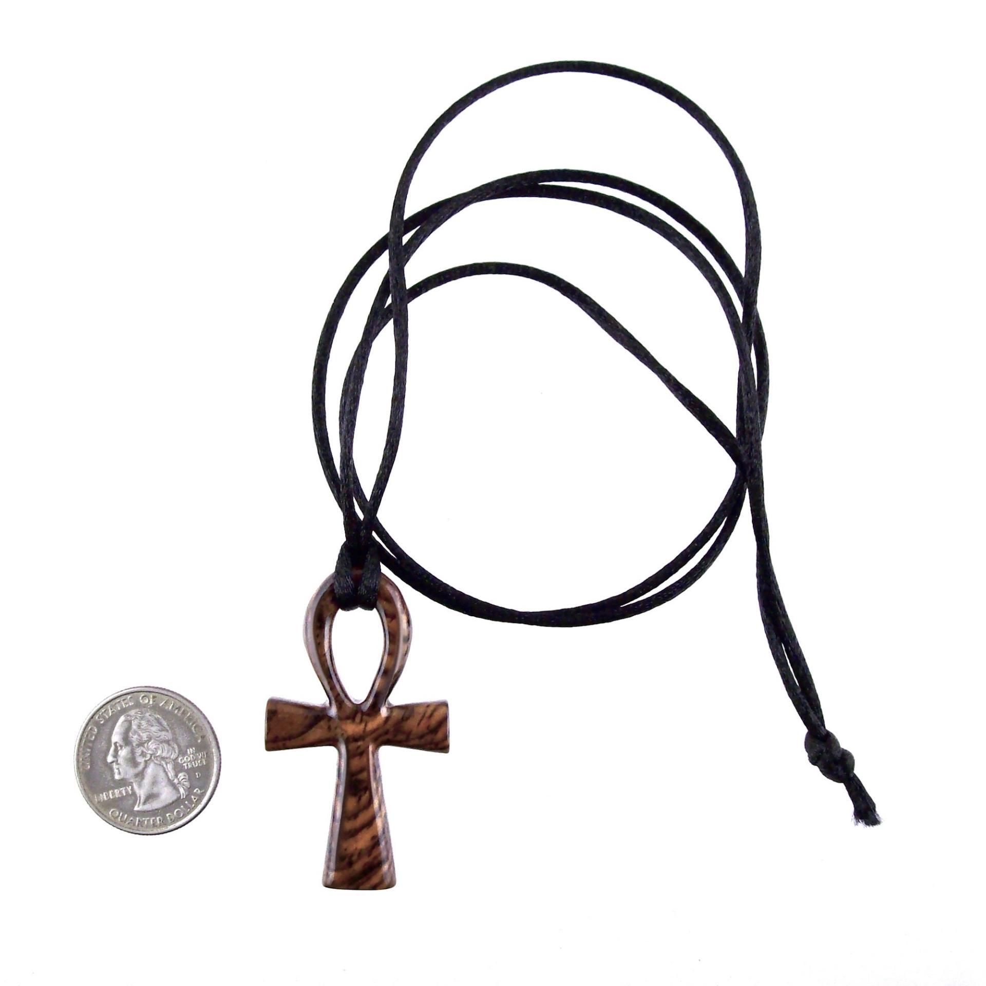 A wooden ankh pendant necklace with a black satin cord ending in a knot. The ankh is reddish-brown with a wood grain pattern.