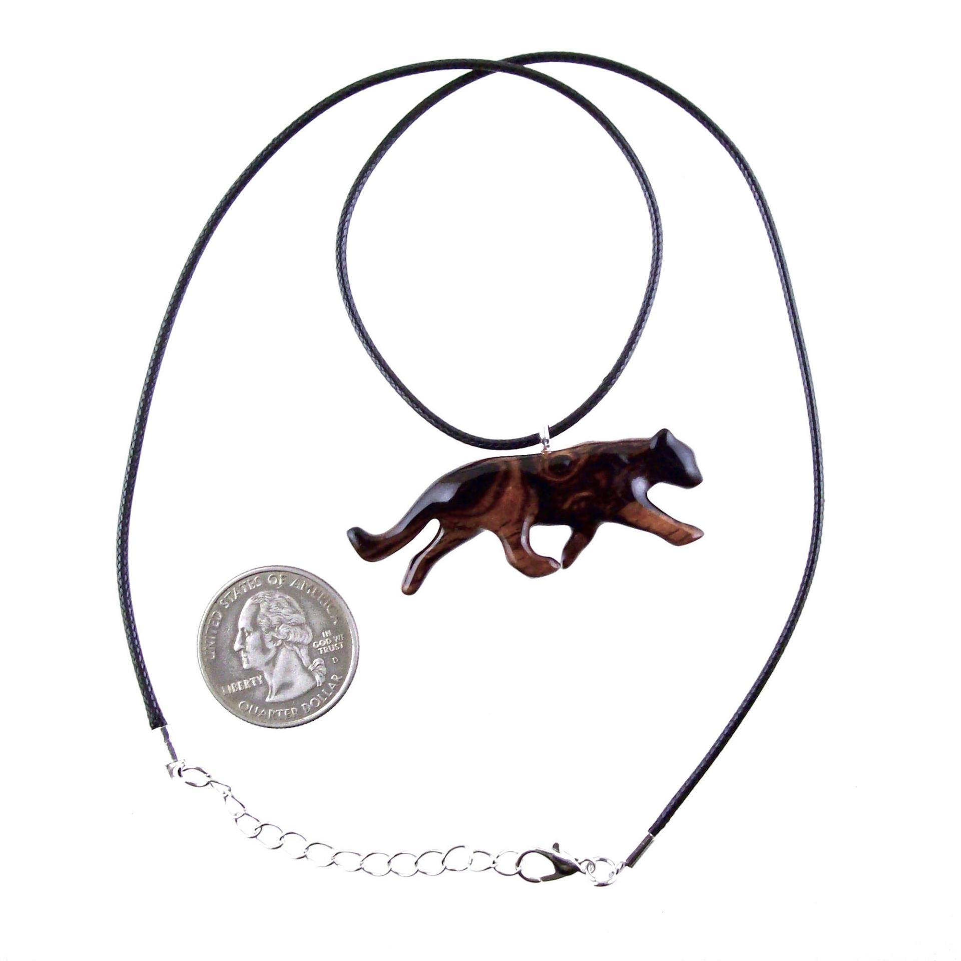 A dark reddish-brown wooden panther necklace pendant hangs from a black cord necklace. The pendant is carved in the shape of a panther in motion.  The necklace includes a silver clasp. A quarter is shown for scale.