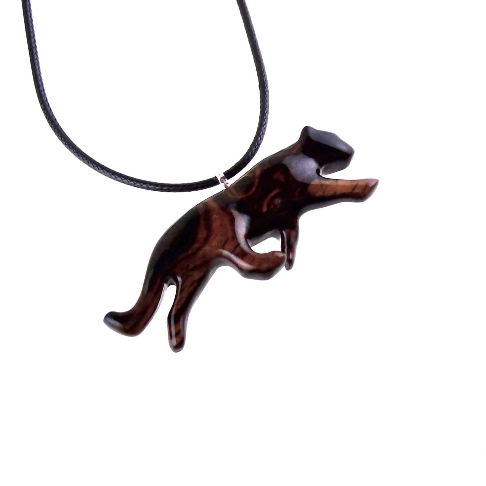 Dark reddish-brown wooden panther necklace pendant on a black cord. The panther is carved in a leaping pose, showcasing intricate wood grain details.  The pendant features a smooth, polished finish and hangs from a simple black cord necklace. This handcrafted necklace is a unique and stylish accessory, perfect for animal lovers and those who appreciate nature-inspired jewelry.