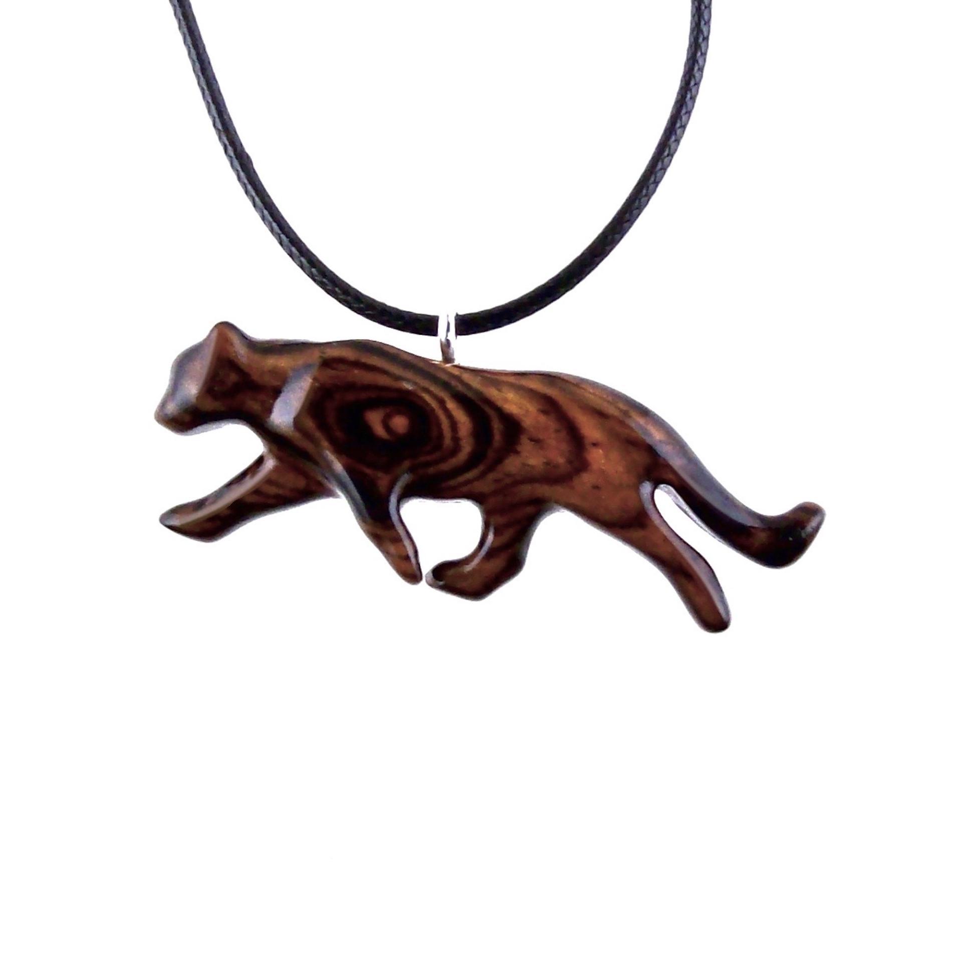 Dark reddish-brown wooden panther necklace pendant on a black cord. The panther is carved from wood with visible wood grain, and is depicted in a mid-stride position.  The pendant features a sleek, stylized design. This handcrafted necklace is a unique and eye-catching piece of jewelry.