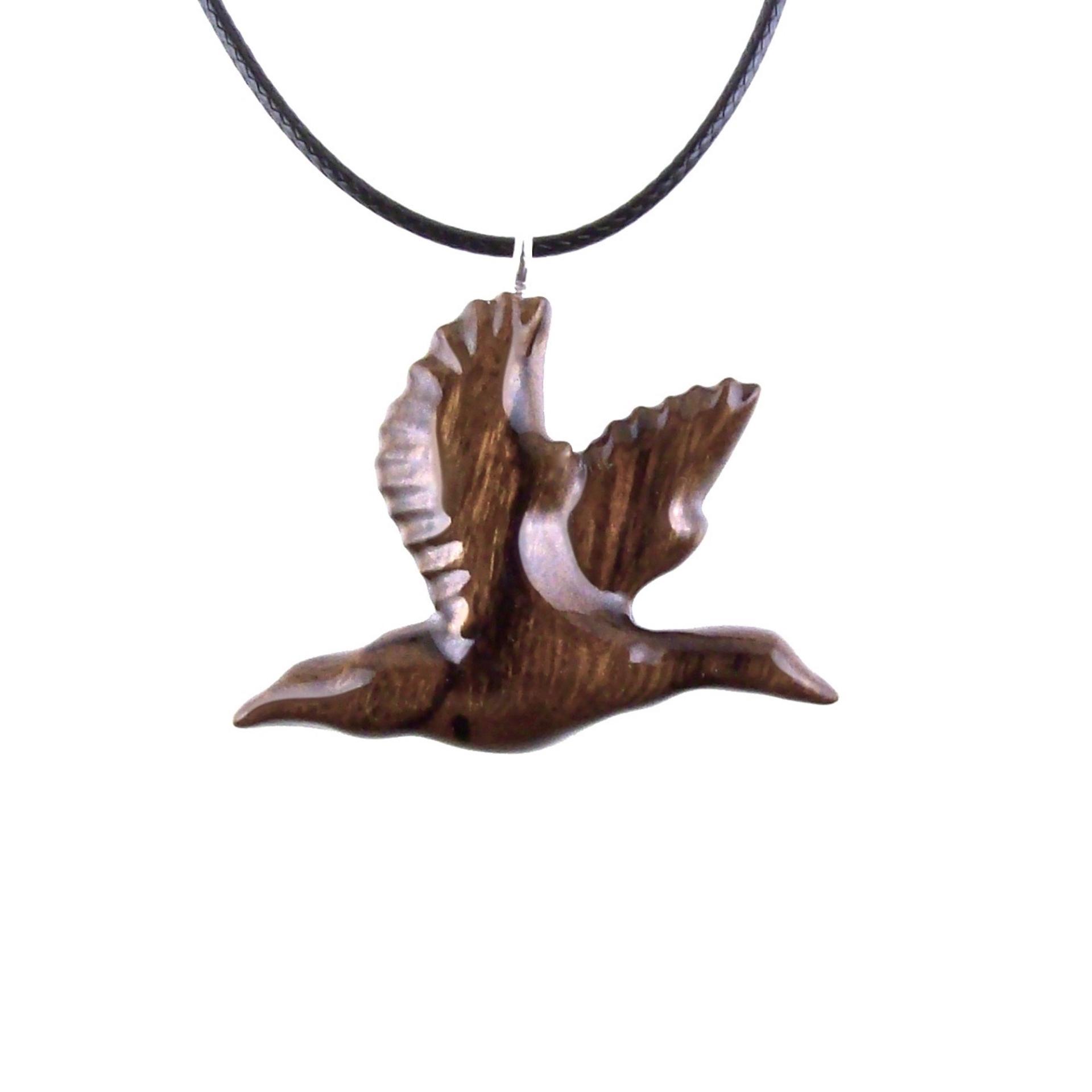 A dark brown wooden duck pendant on a black cord necklace. The bird is carved in flight with its wings spread out.