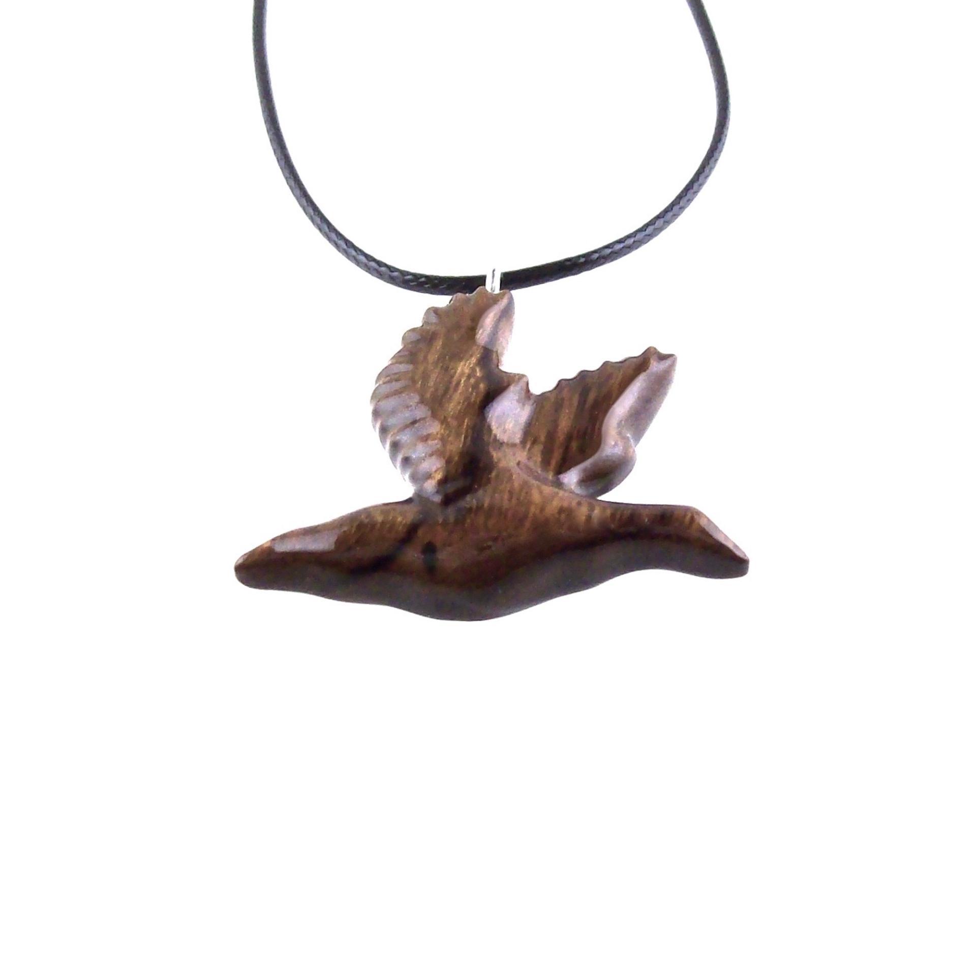 A dark brown wooden duck pendant on a black cord necklace. The bird is carved in flight with its wings spread out.