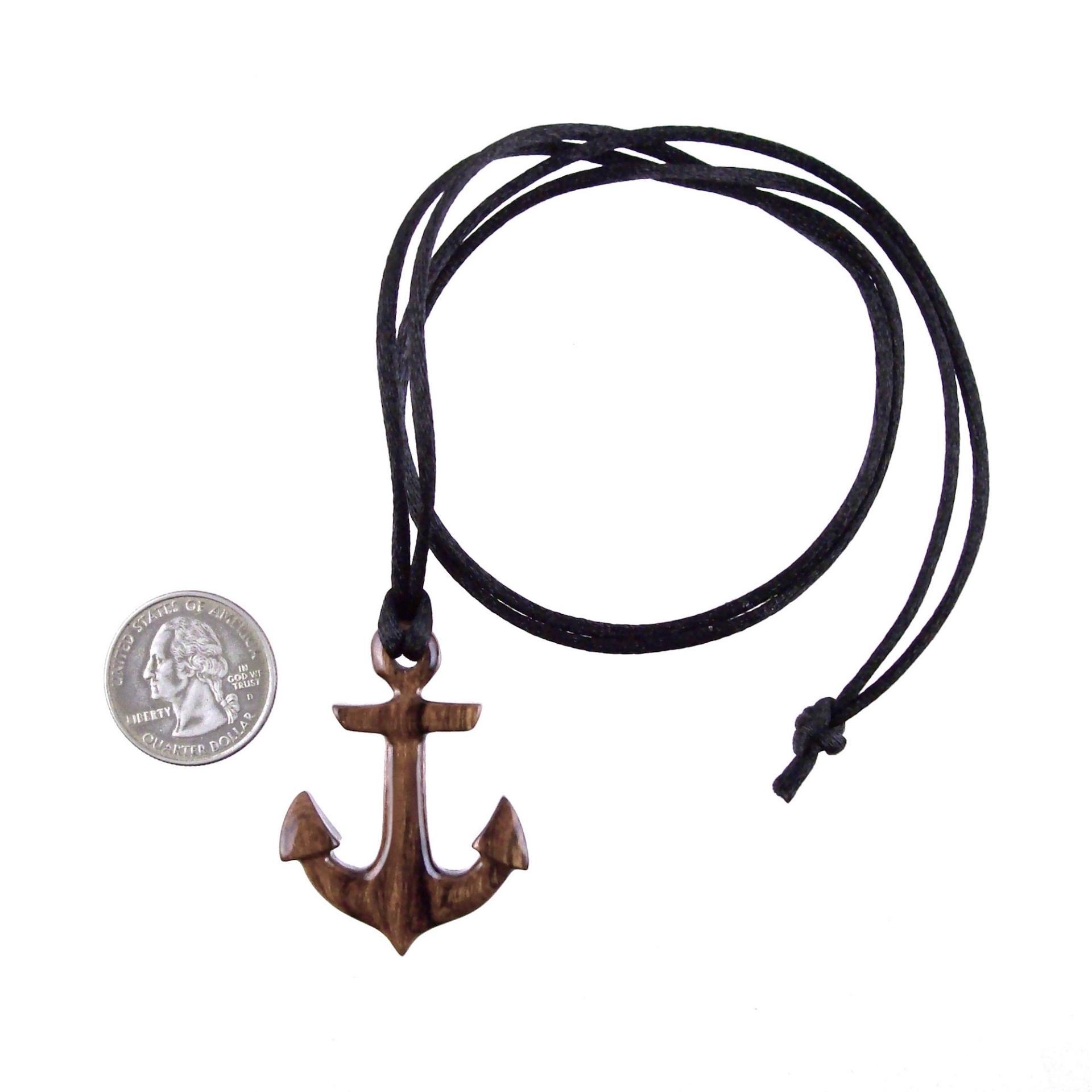 A wooden anchor pendant necklace with black satin cord ending with a knot next to a US quarter for scale.