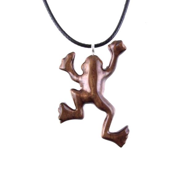 A brown frog pendant on a black cord necklace. The frog is in a jumping pose with its legs outstretched.